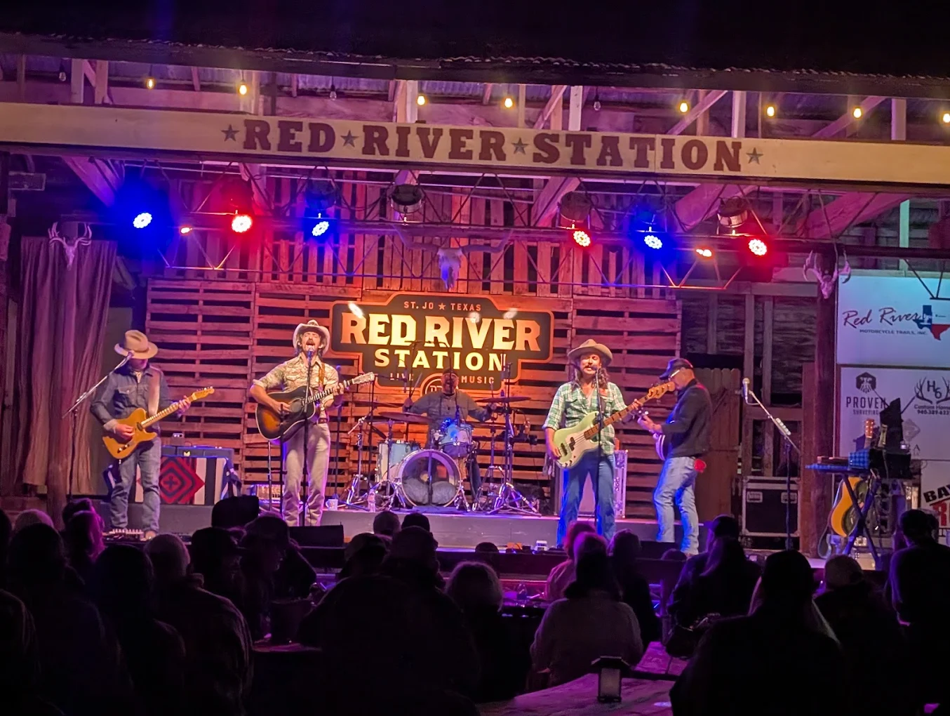 Band performing under the lit Red River Station stage sign in Saint Jo, Texas