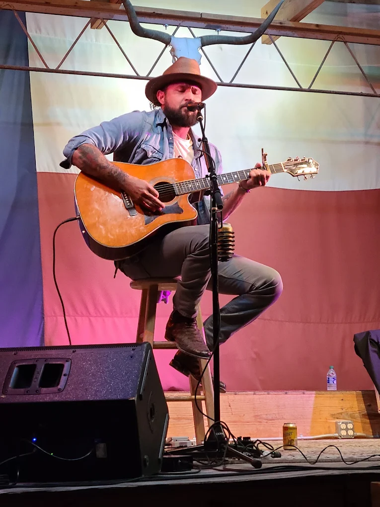 Solo singer-songwriter performing acoustic in front of the Texas flag